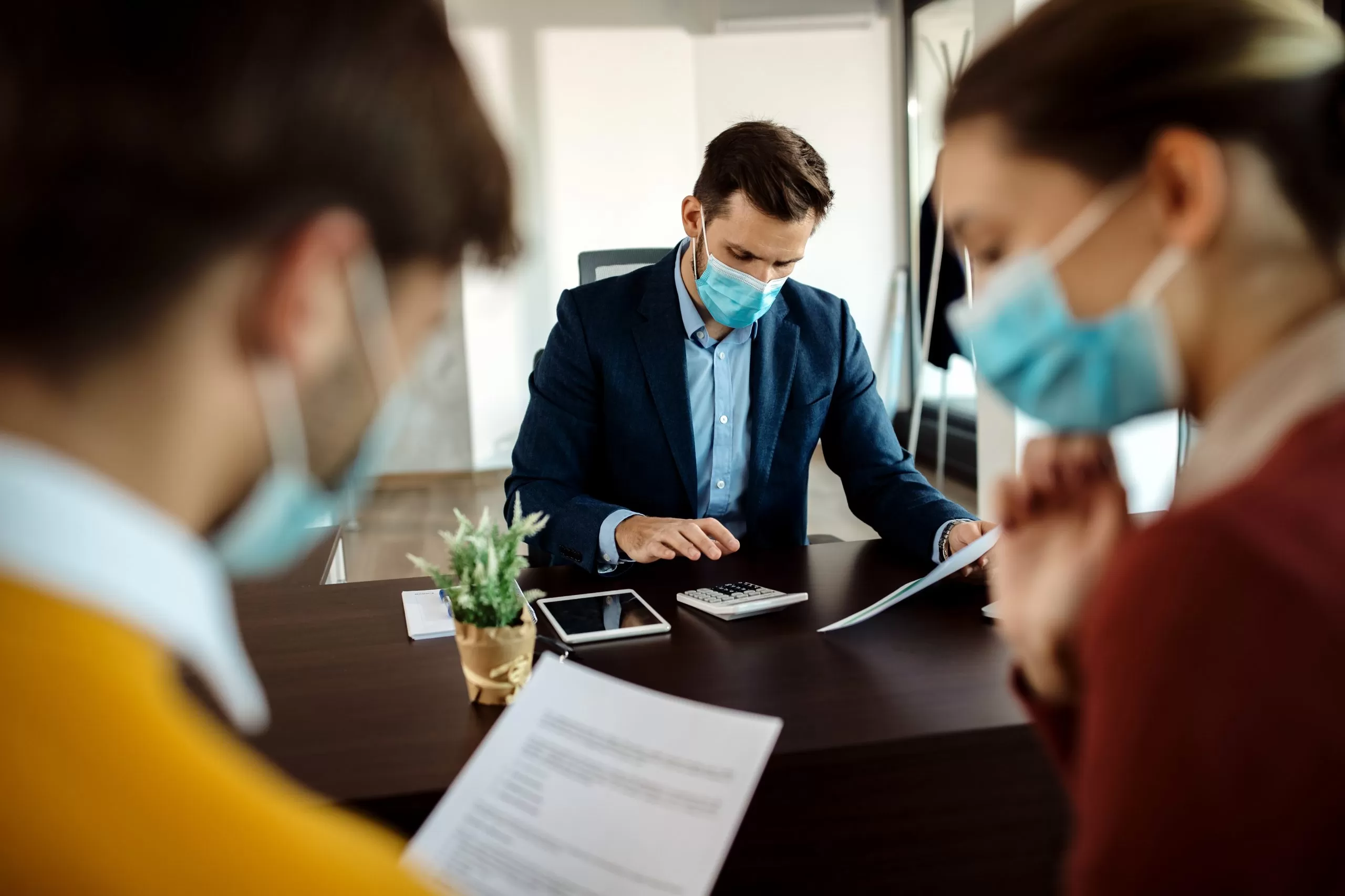 Start a business in USA - Best business consultant in virginiainsurance agent with face mask calculating costs while having meeting with clients office scaled
